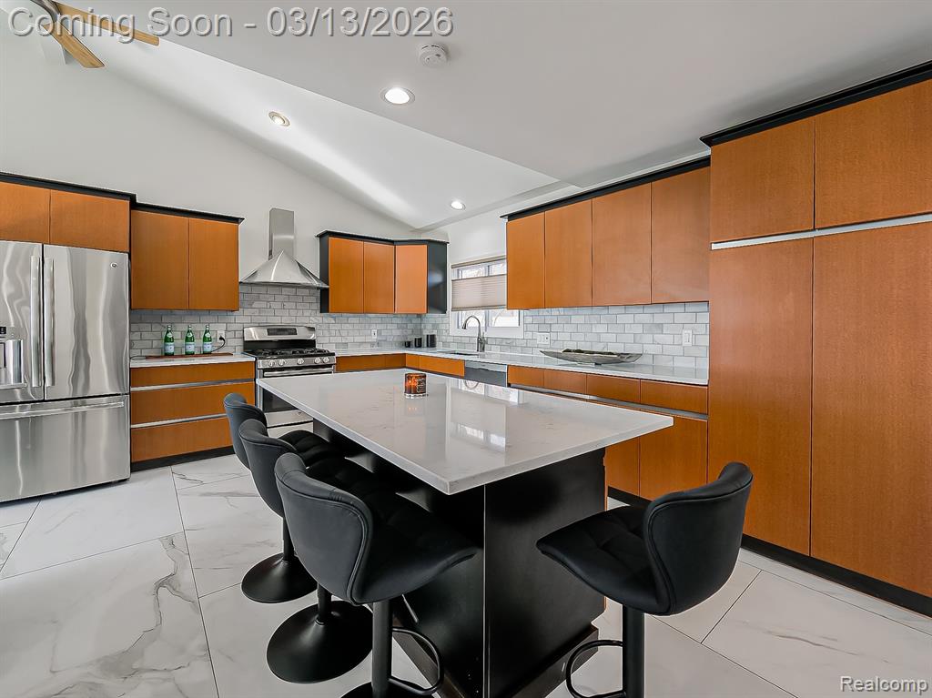Kitchen featuring a kitchen island, a breakfast bar area, open floor plan, recessed lighting, and light stone countertops