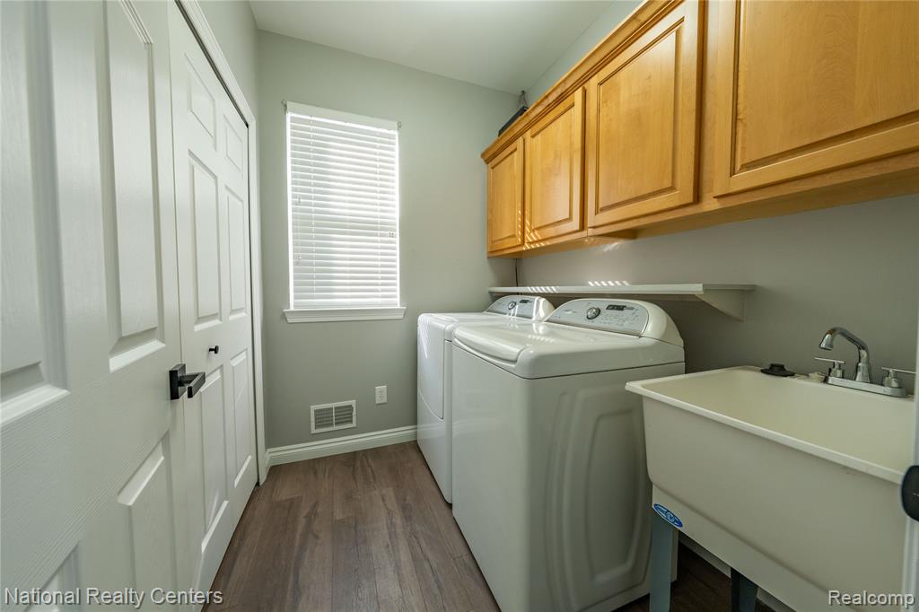 Laundry area featuring dark wood-style flooring, washer and clothes dryer, and cabinet space