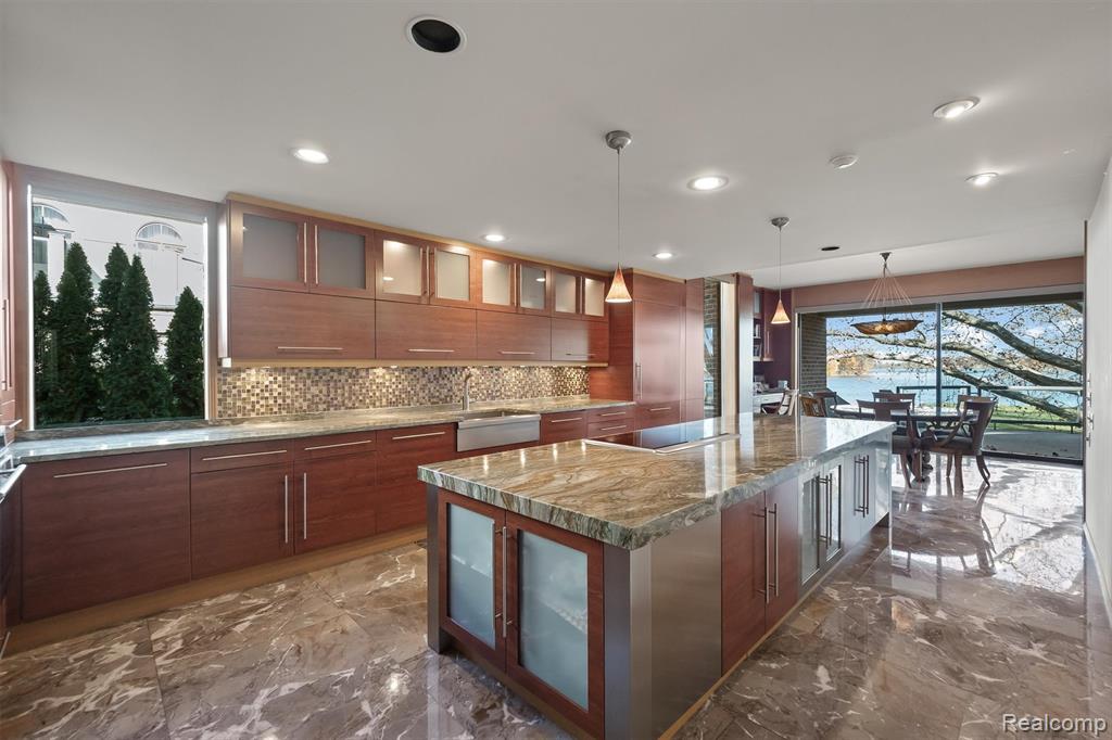 Kitchen featuring glass insert cabinets, dark marble finish flooring, light stone countertops, decorative backsplash, and a kitchen island