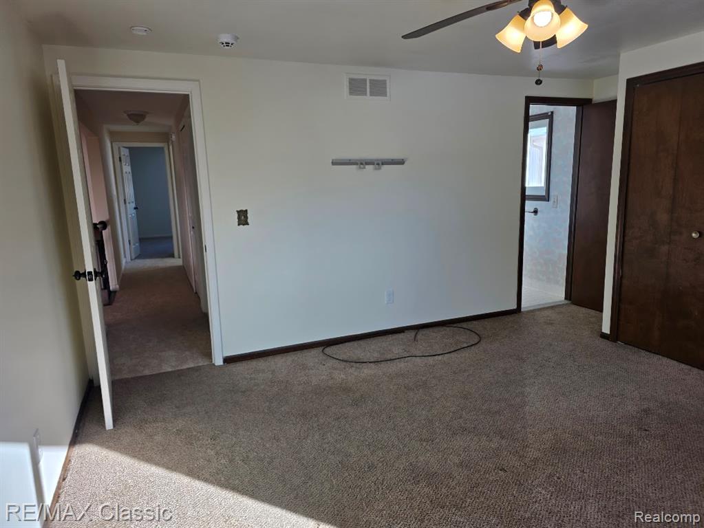 Unfurnished bedroom with carpet, a ceiling fan, and a closet