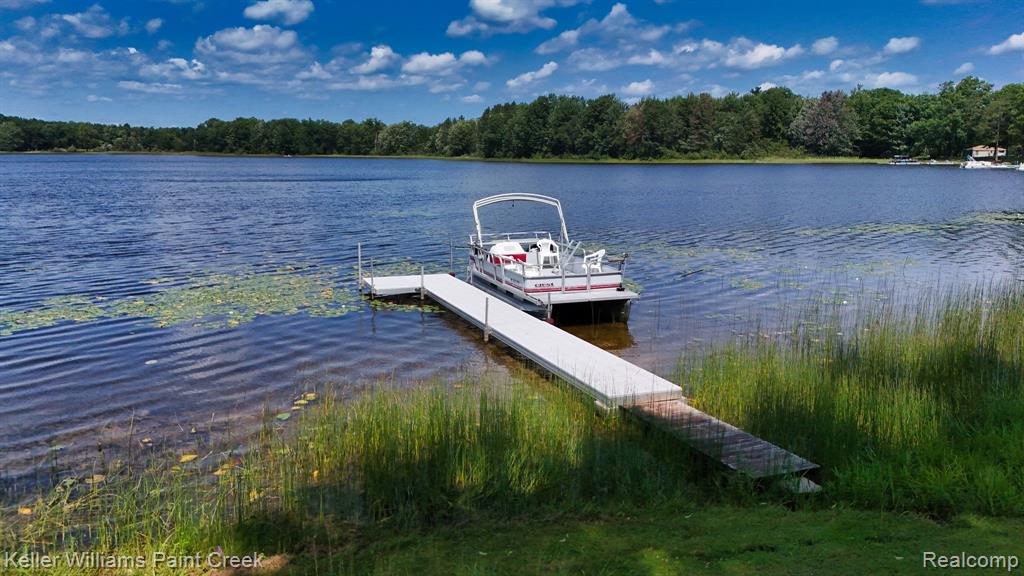 Waterfront property featuring a private dock, lake access, and surrounding mature trees