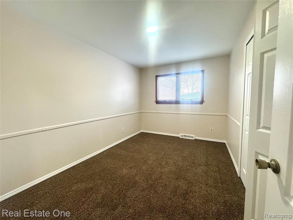 Empty room with dark carpet and baseboards