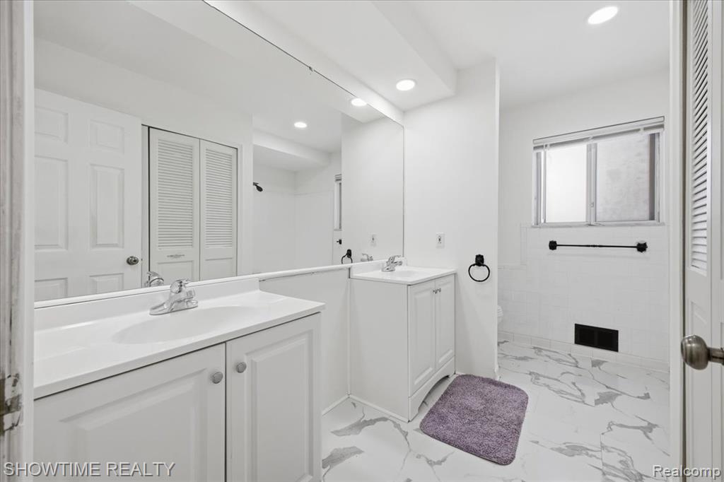 Full bath with a closet, light marble finish floors, two vanities, and recessed lighting