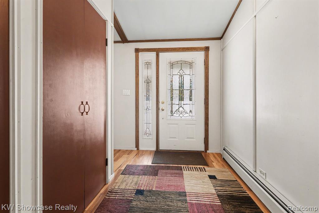 Entrance foyer featuring baseboard heating, light wood-style flooring, and crown molding