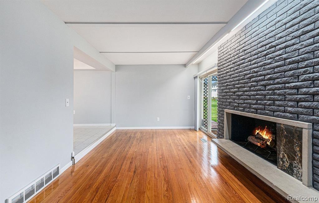 Unfurnished living room featuring a brick fireplace and light wood finished floors