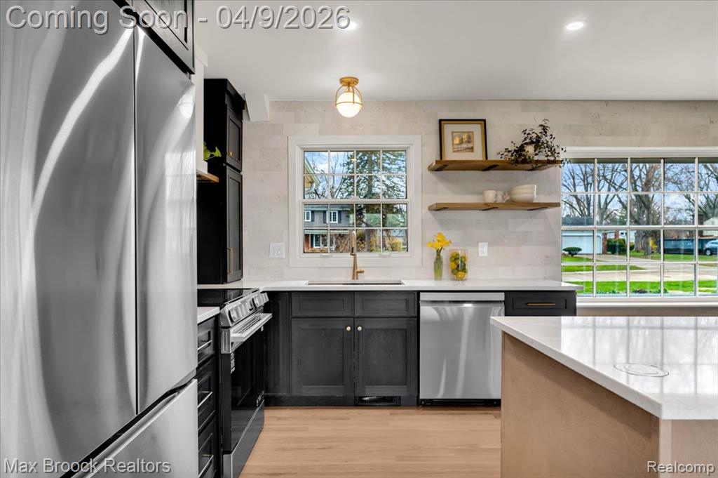 Kitchen featuring stainless steel appliances, open shelves, light stone countertops, light wood-style flooring, and recessed lighting