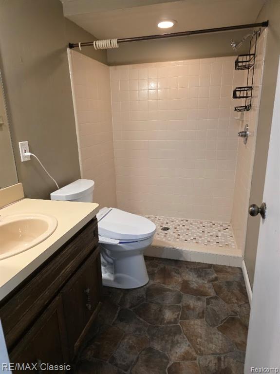 Bathroom featuring stone tile floors, vanity, and a stall shower