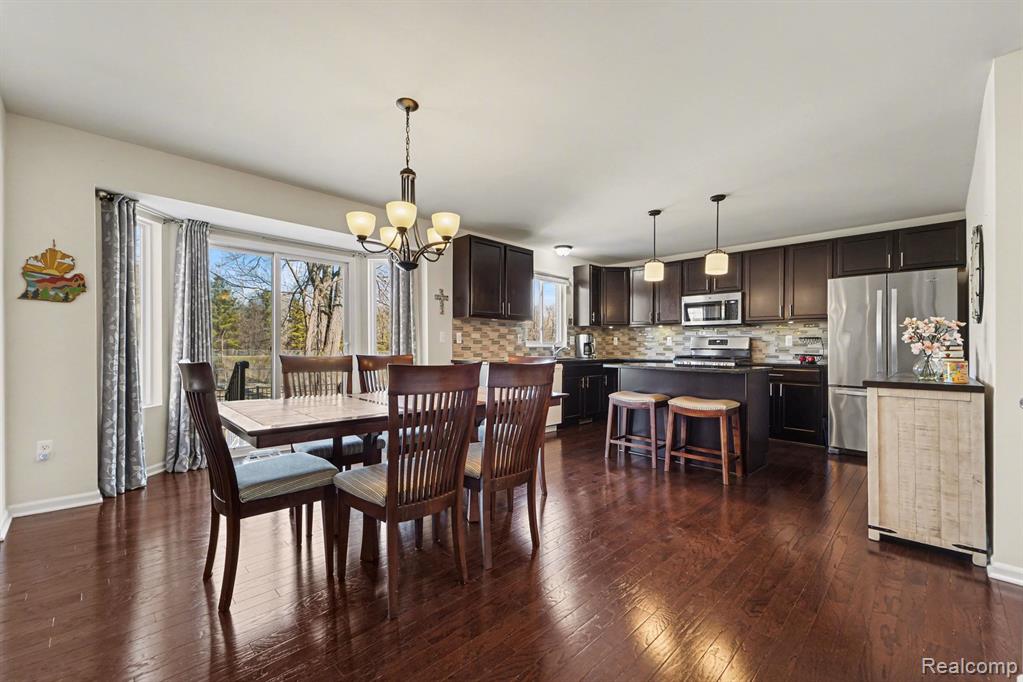 Dining space with suspended lighting and dark wood-type flooring
