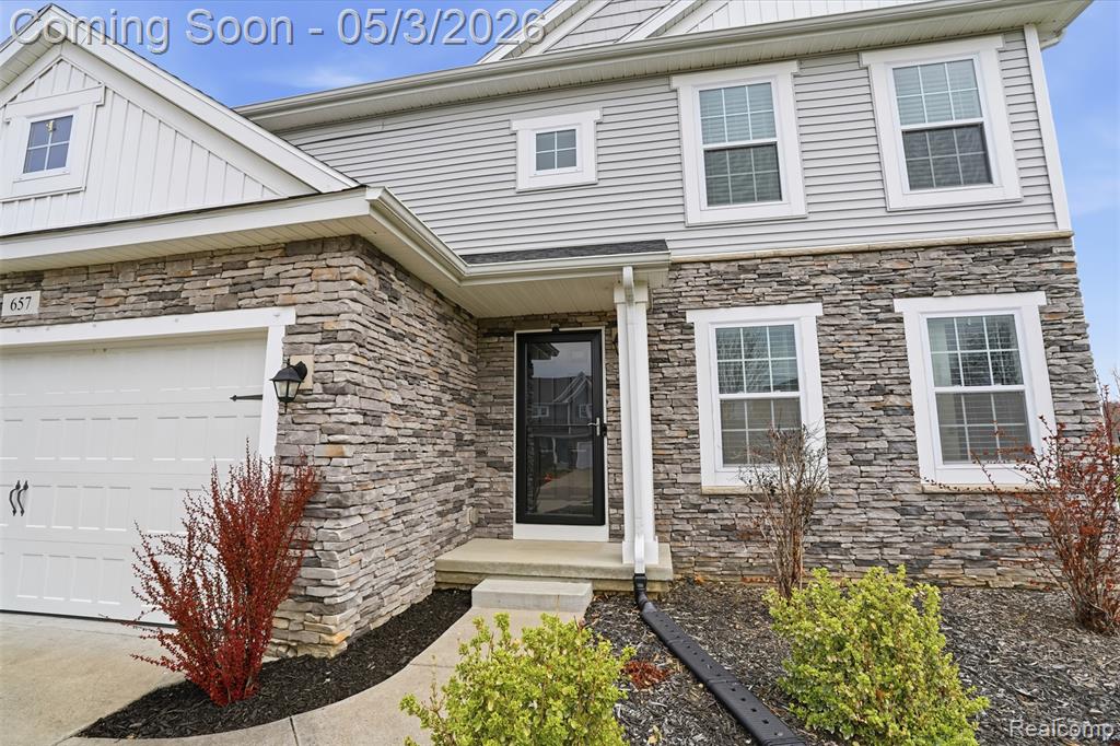 Doorway to property with stone siding and a garage