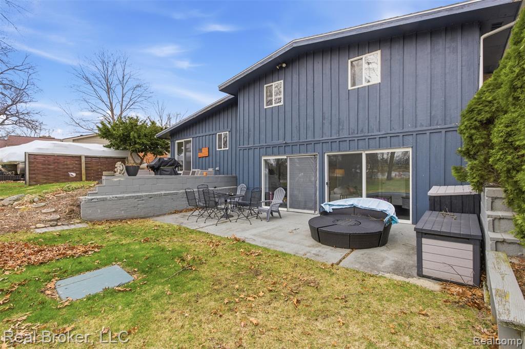 Rear view of property with board and batten siding, a patio area, and a lawn