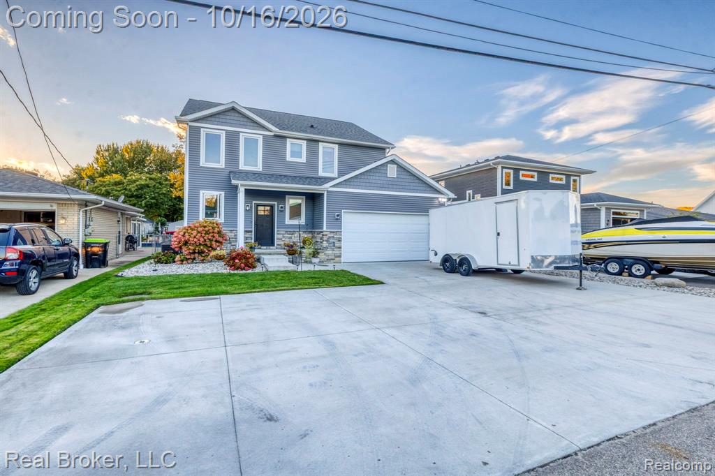 Two-story residence featuring horizontal and shake siding, stone veneer accents, an attached two-car garage, and concrete driveway