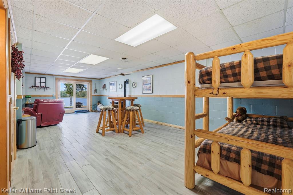 Wood-finish flooring, drop ceiling with recessed lighting, light blue and white two-tone walls, and a sliding glass door