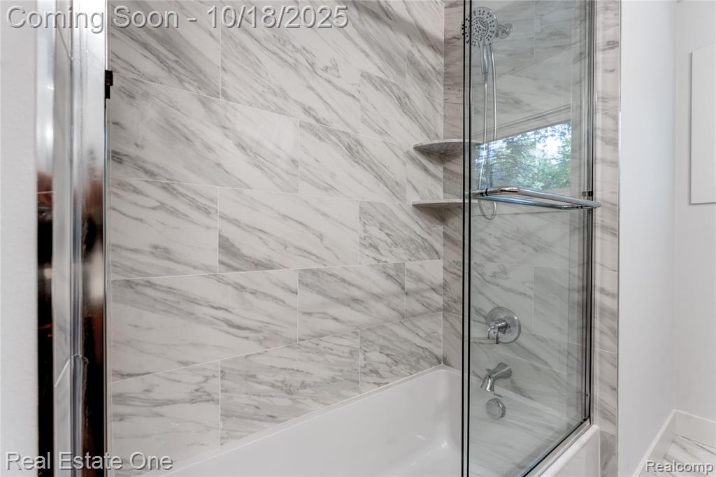 Bathroom featuring combined bath / shower with glass door
