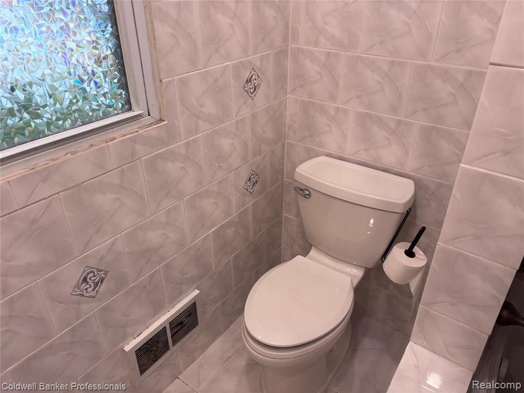 Half bath with tile walls and tile patterned floors