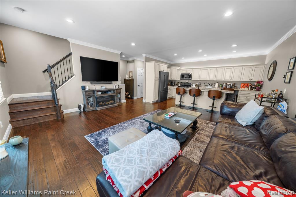 Living room with ornamental molding, dark wood-style floors, and recessed lighting