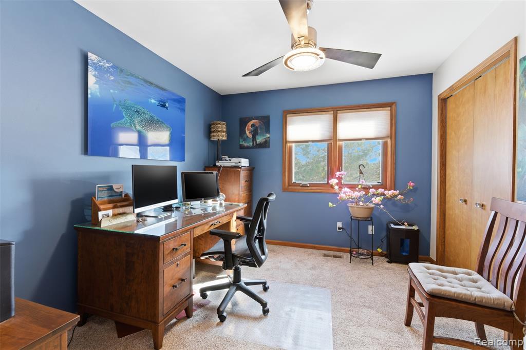 Office area featuring light carpet and ceiling fan
