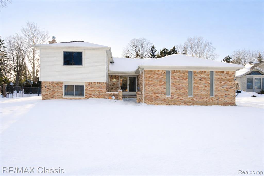 View of front of property with brick siding and a chimney