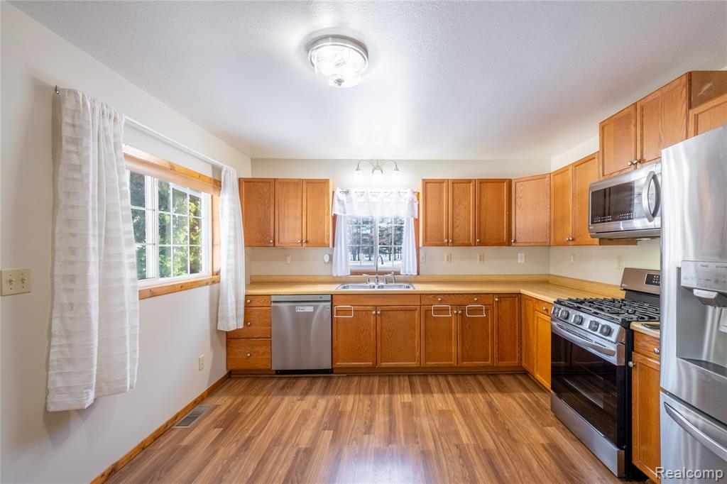 Kitchen with stainless steel appliances, light countertops, light wood-style flooring, and brown cabinets