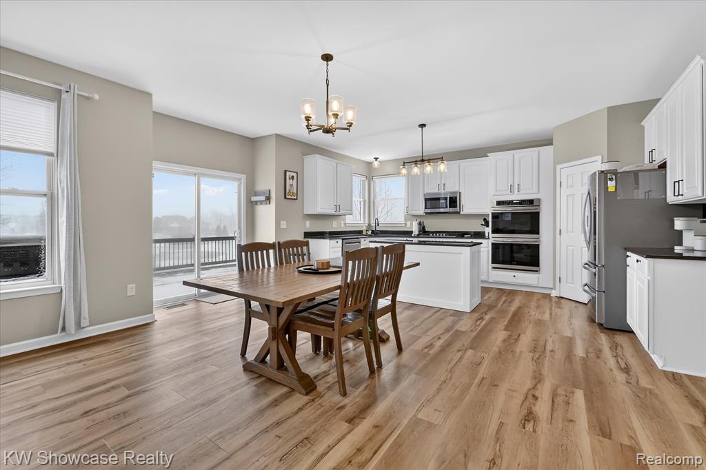 Dining room with light wood-style floors, a raised ceiling, and a chandelier