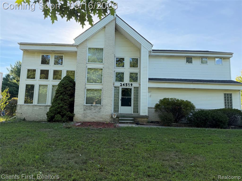 Two-story facade with light-colored siding, a prominent gabled entry, and multiple large windows
