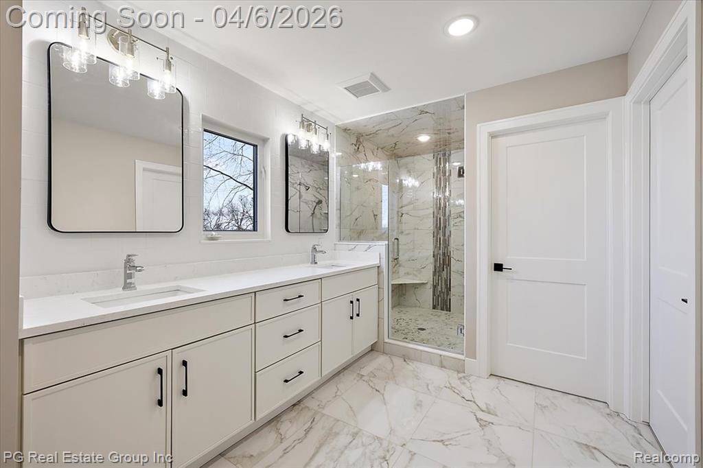 Full bathroom with double vanity, a marble finish shower, light marble finish flooring, and recessed lighting