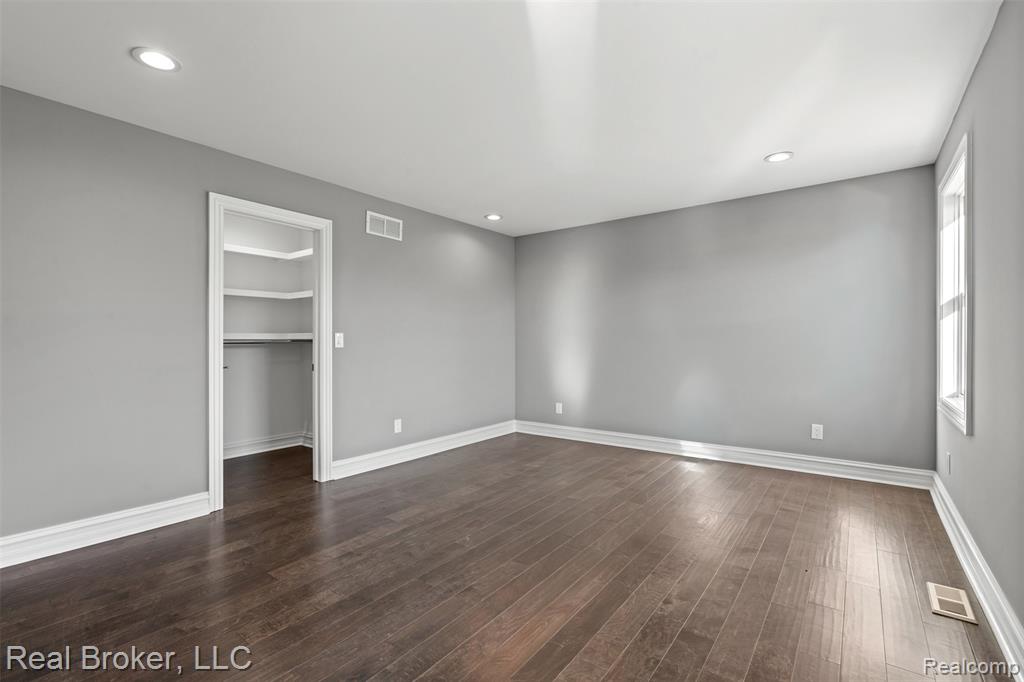 Unfurnished bedroom featuring a spacious closet, recessed lighting, and dark wood-type flooring