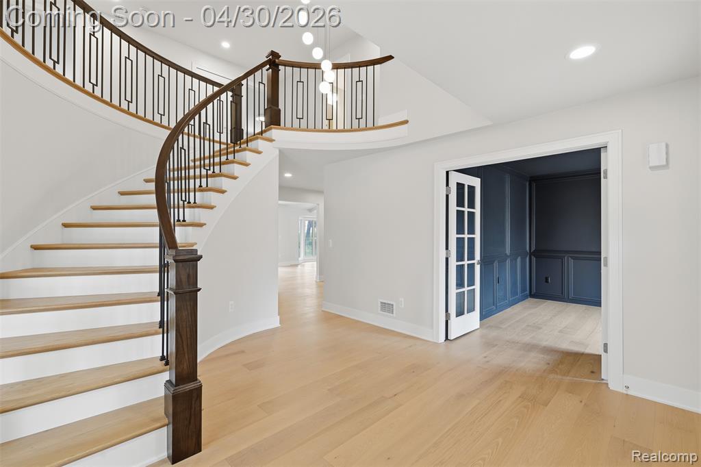 Stairway with wood finished floors, recessed lighting, and a high ceiling