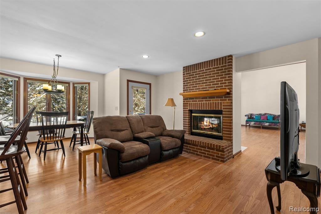 Living room with a fireplace, light wood finished floors, and recessed lighting