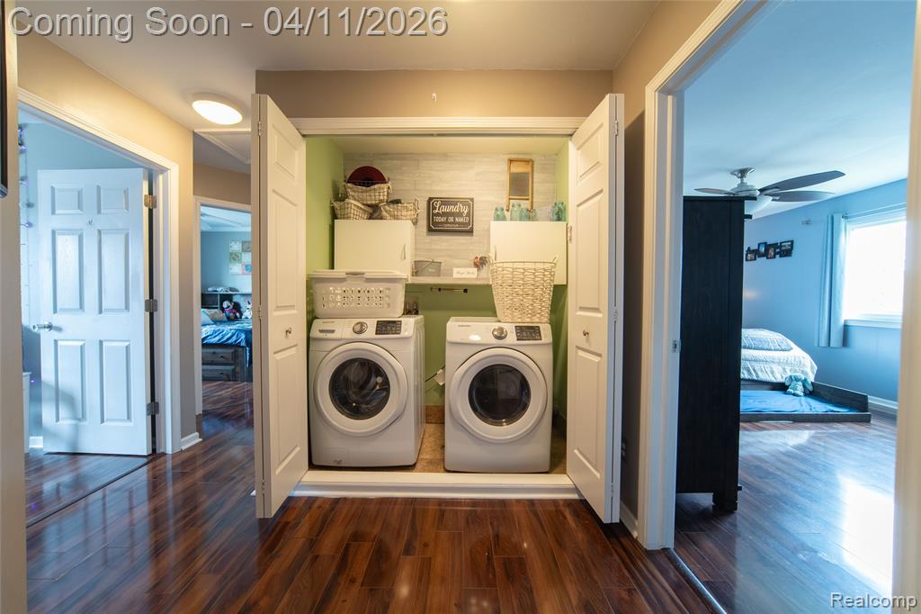 Laundry area featuring dark wood finished floors, separate washer and dryer, and a ceiling fan