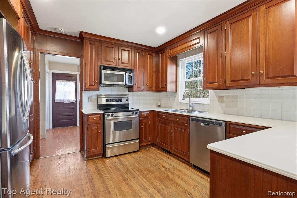 Kitchen with freestanding refrigerator, light countertops, light wood-style floors, recessed lighting, and wood finish cabinetry