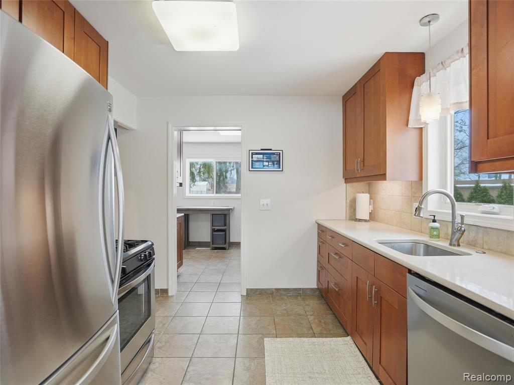 Kitchen with wood finish cabinetry, stainless steel appliances, and light stone countertops