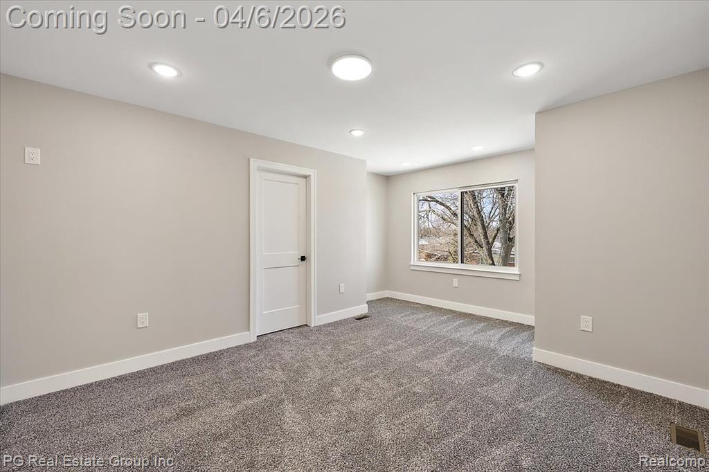 Empty room with dark colored carpet and recessed lighting