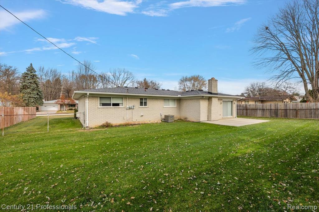 Rear view of property featuring a fenced backyard, a patio area, a chimney, and brick siding