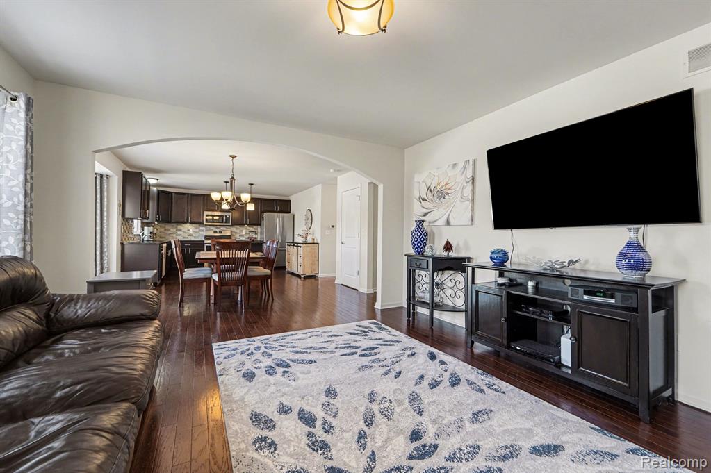 Living area featuring dark wood-type flooring, hanging lights, and arched walkways