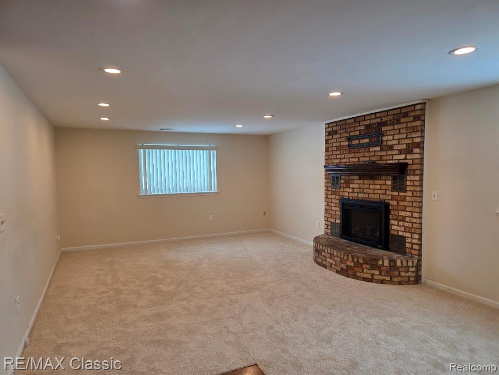 Unfurnished living room with a fireplace, recessed lighting, and light carpet