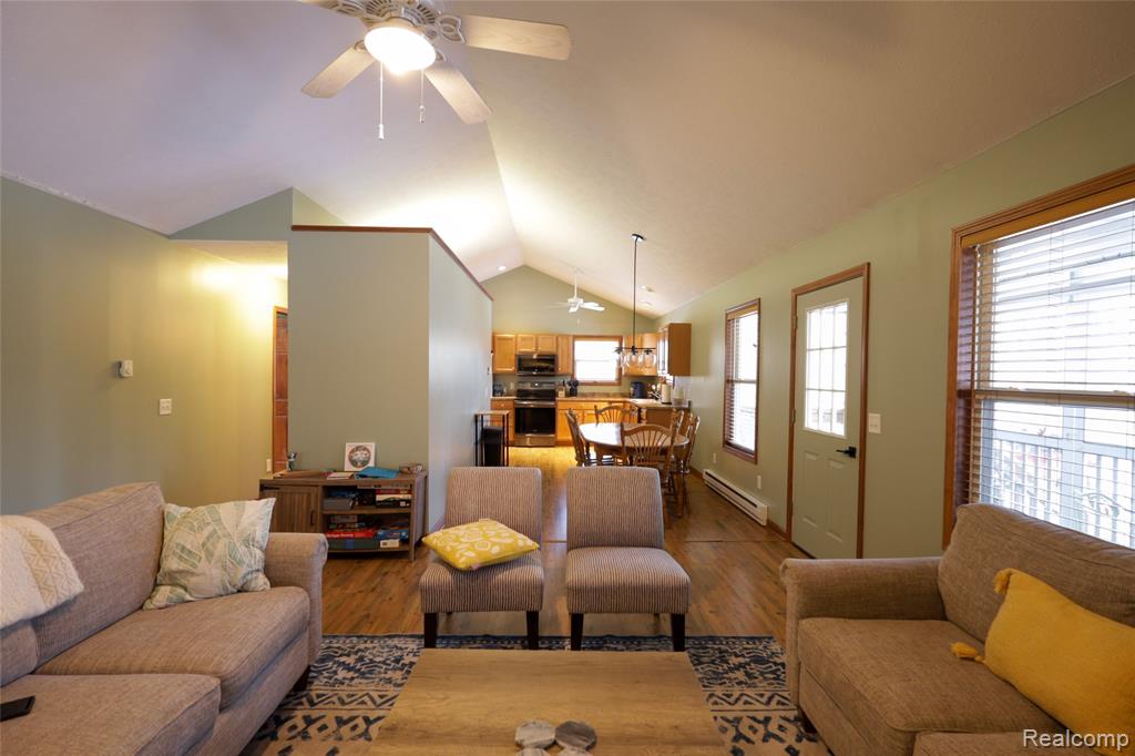 Living room featuring a ceiling fan, a baseboard radiator, and wood finished floors