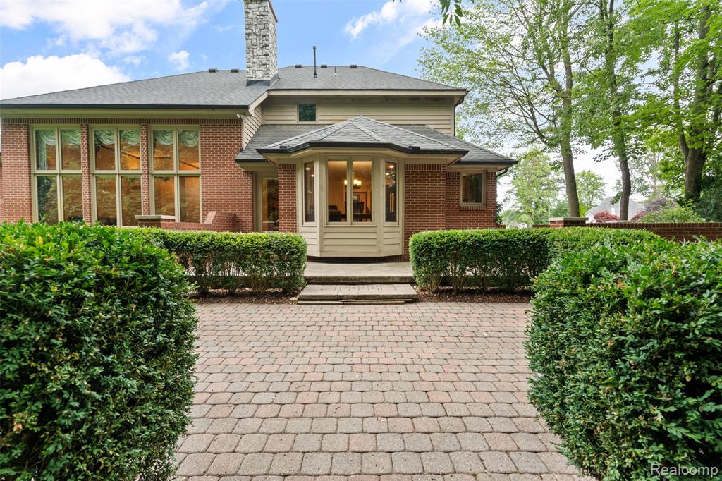 Rear view of property featuring a chimney, a patio area, and brick siding
