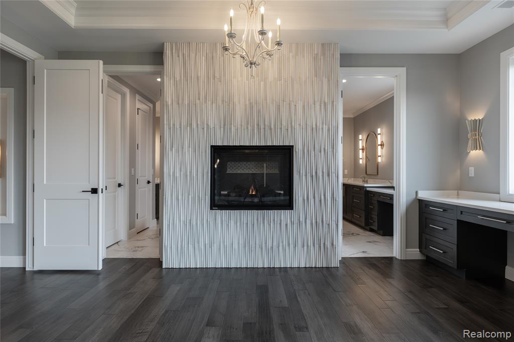 Unfurnished living room featuring ornamental molding, a chandelier, a fireplace, and dark wood-type flooring