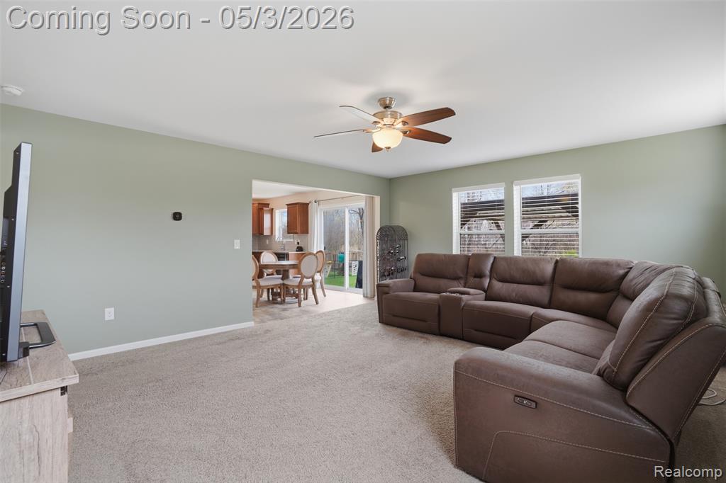 Living area with ceiling fan and light carpet