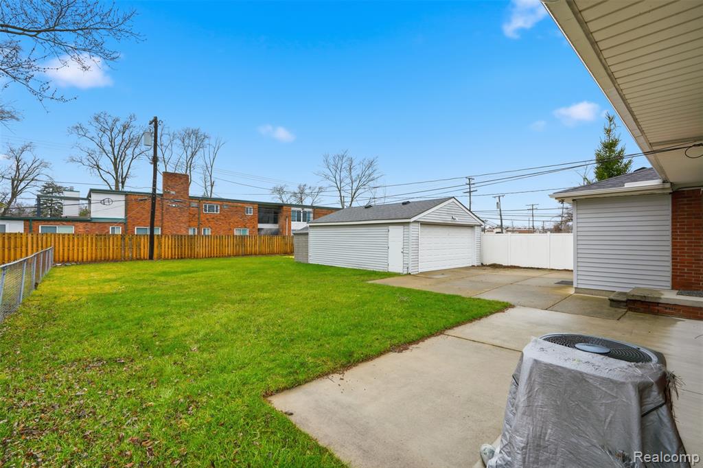 Fenced backyard featuring an outdoor structure, a garage, and a patio