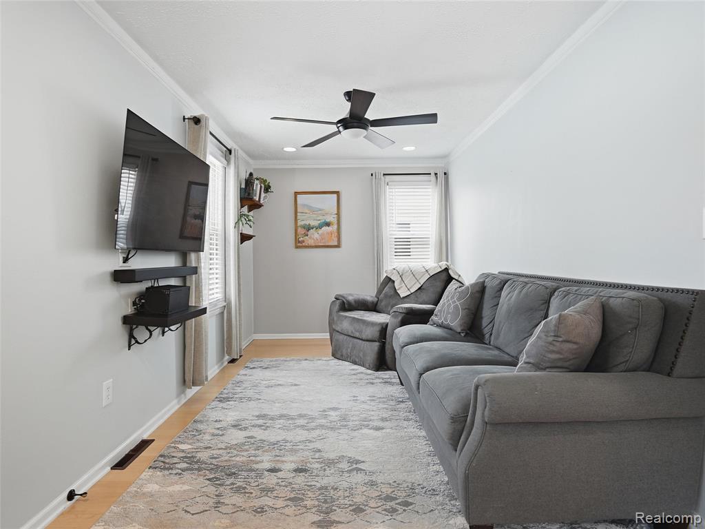Living area featuring plenty of natural light, ceiling fan, light wood finished floors, ornamental molding, and recessed lighting