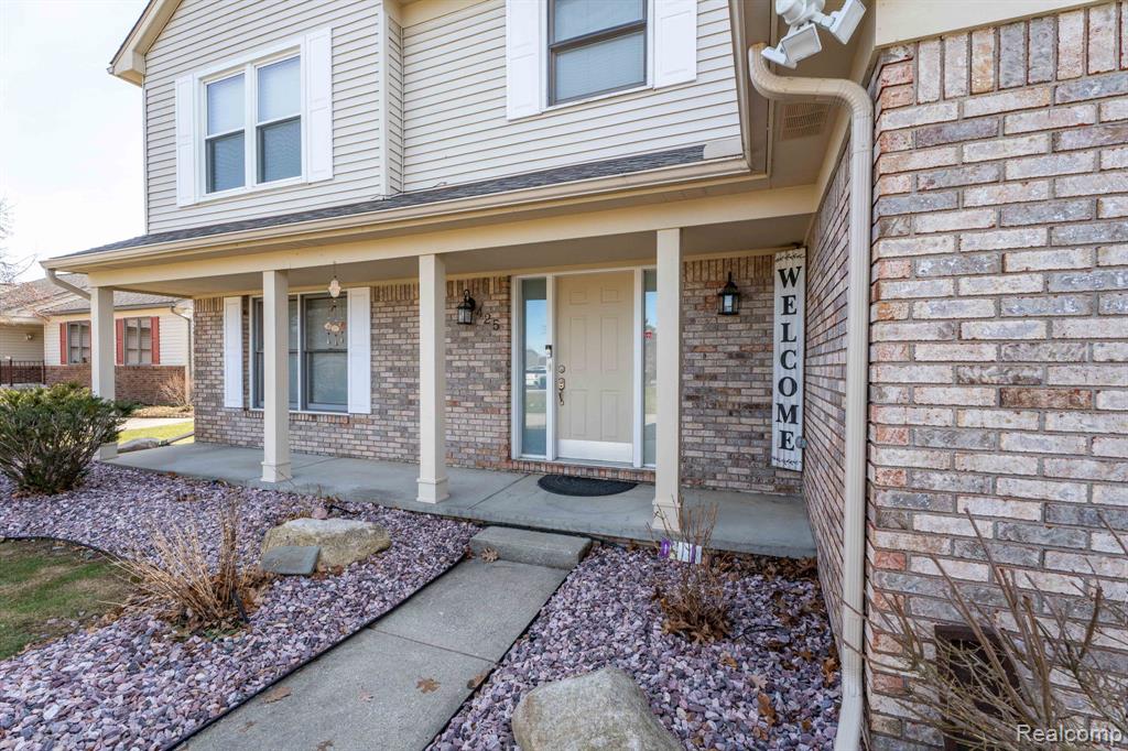 View of exterior entry featuring brick siding and covered porch