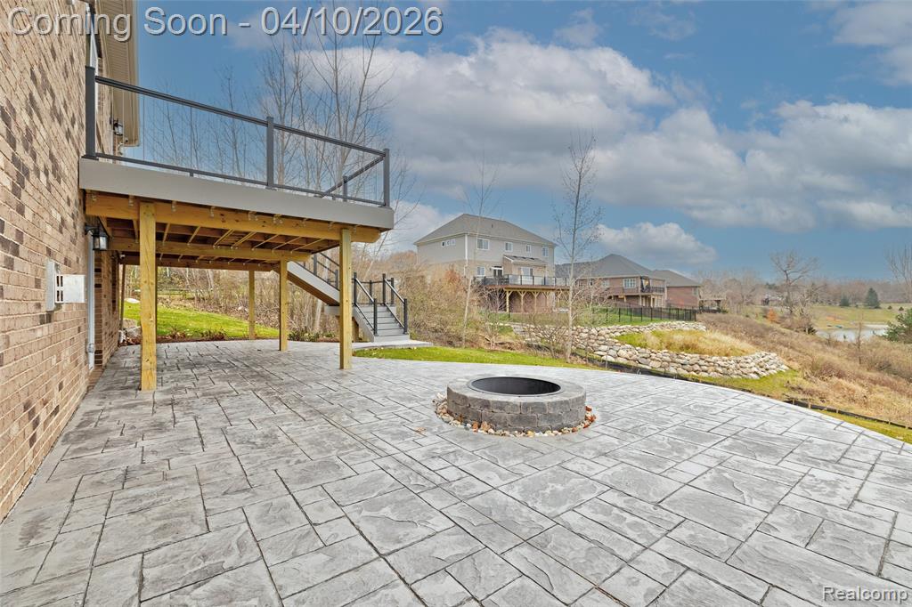 View of patio featuring a fire pit, a wooden deck, and a residential view