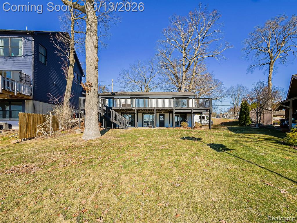 Back of property with a patio, an attached garage, a lawn, and a wooden deck
