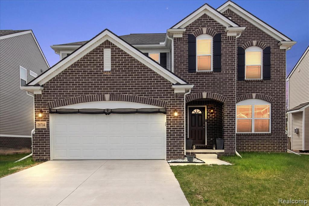 View of front facade featuring brick siding, driveway, and a front yard