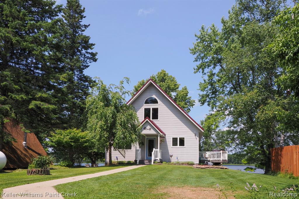 Siding exterior with a gable roof, arch-top window, and an elevated wood deck