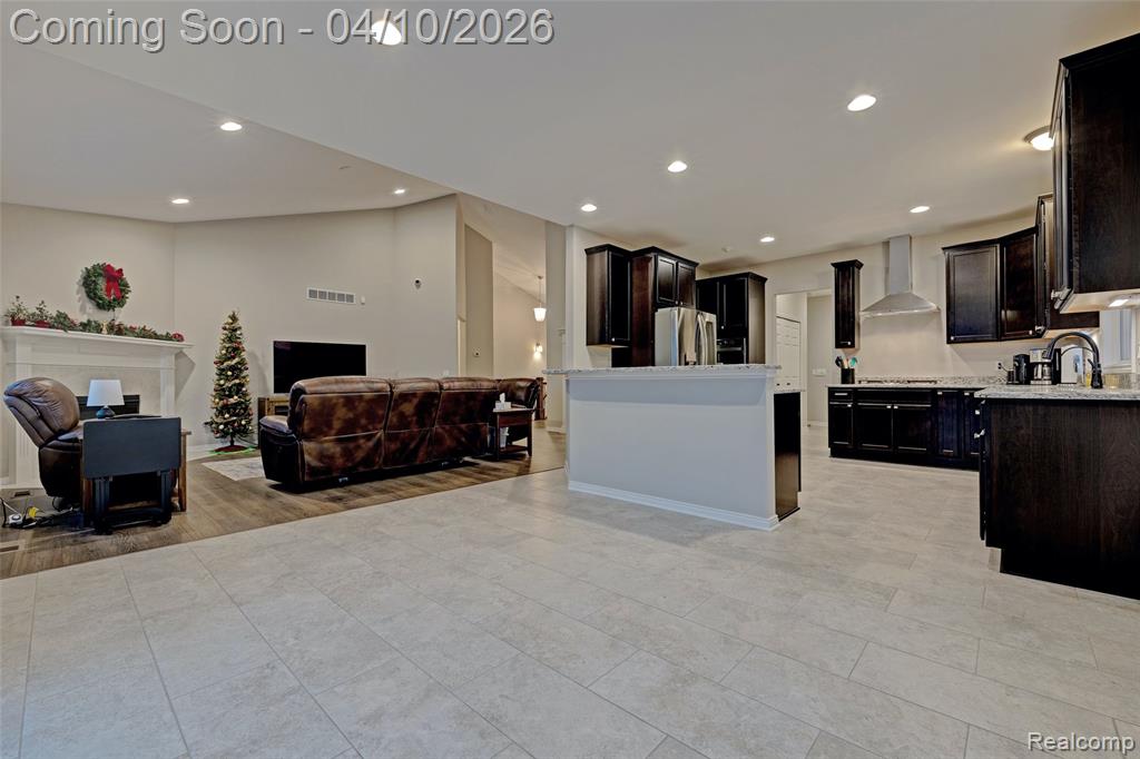 Kitchen featuring open floor plan, dark wood finish cabinetry, stainless steel appliances, recessed lighting, and a fireplace