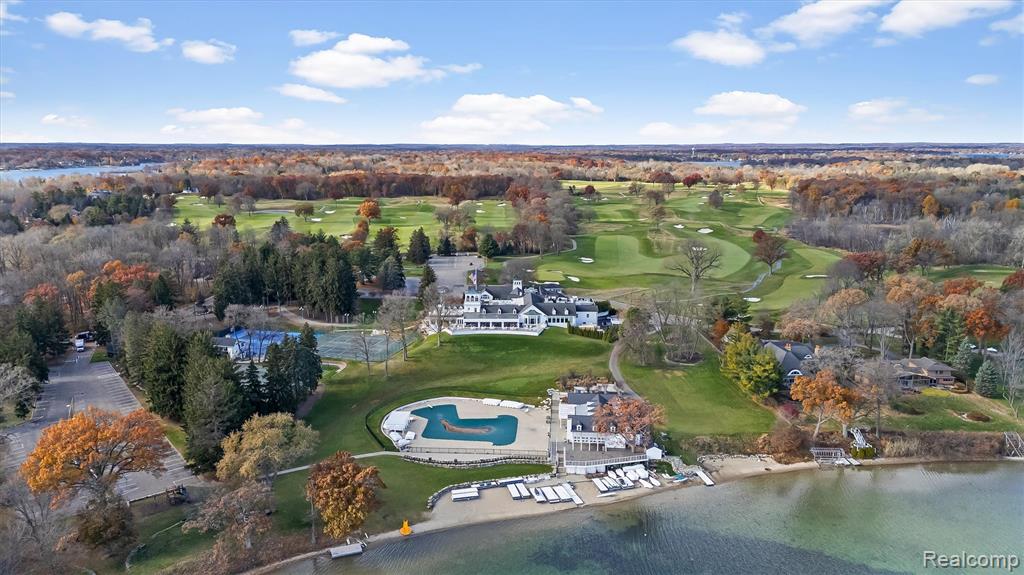 Aerial view of property and surrounding area featuring a pool area and a golf course