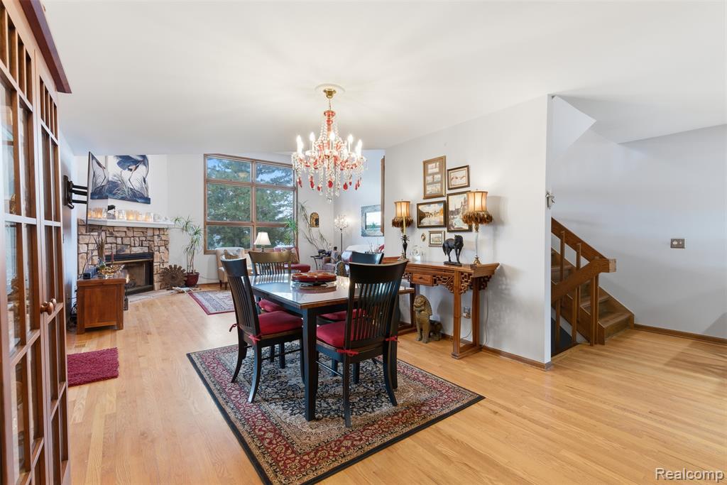 Dining space with light wood-style flooring, suspended lighting, and a fireplace