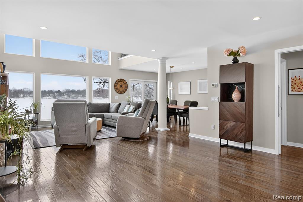 Living room with dark wood-style flooring, a fireplace, ornate columns, and recessed lighting